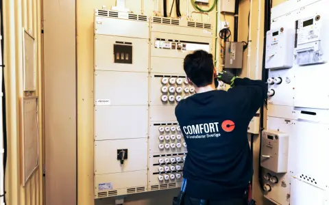 En elektriker arbetar vid en elcentral med många säkringar och mätare. För säkerheten måste man ha jordfelsbrytare.
