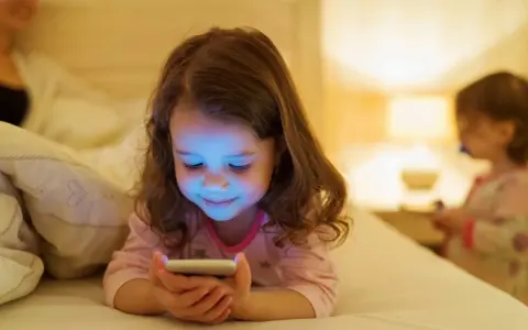 Dziewczynka zafascynowana ekranem telefonu. Jak odzwyczaić dziecko od telefonu? Czas na alternatywy!