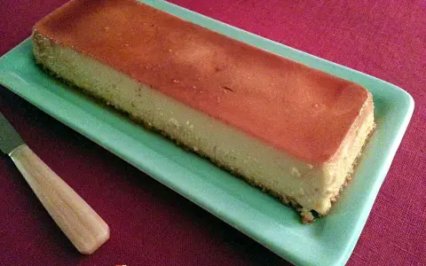 Un délicieux flan antillais, doré et onctueux, prêt à être dégusté sur une assiette verte.