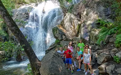 Niños exploran la Garganta de las Nogaleas, disfrutando de una cascada y la naturaleza.