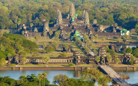 Majestatyczna świątynia Angkor Wat w Siem Reap, otoczona bujną zielenią, z mostem i jeziorem w tle.