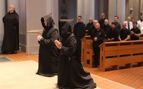 Monk characteristics are evident in the solemn robes and prayerful stances of individuals in a church setting.