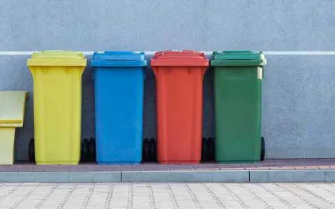 Kolorowe pojemniki na śmieci, w tym żółty, niebieski, czerwony i zielony, stoją obok siebie. Mogą służyć do segregacji odpadów, w tym potencjalnie kod odpadów medycznych igły.