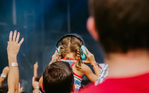 Une jeune fille aux tresses bleues porte un casque anti-bruit pour contrôler le niveau sonore d'un concert.