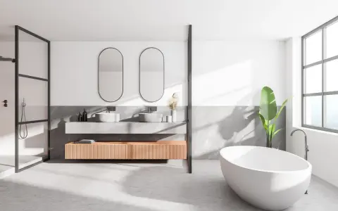Salle de bain moderne avec baignoire îlot, double vasque et douche. Le sol en béton ciré, un carrelage sans joint, crée une ambiance épurée et contemporaine.