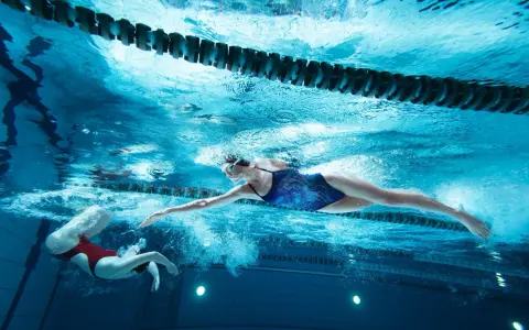 Deux nageuses en action, l'une effectuant une culbute natation, l'autre nageant le crawl sous l'eau.