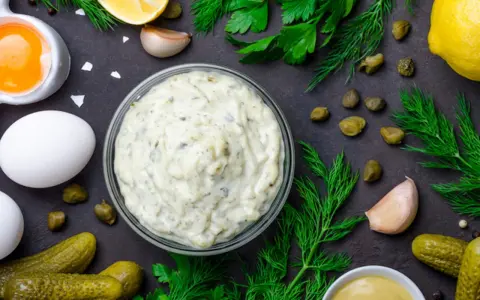 Ingredienti freschi per una deliziosa salsa tartara: uova, cetriolini, capperi, limone, aglio, aneto e prezzemolo.