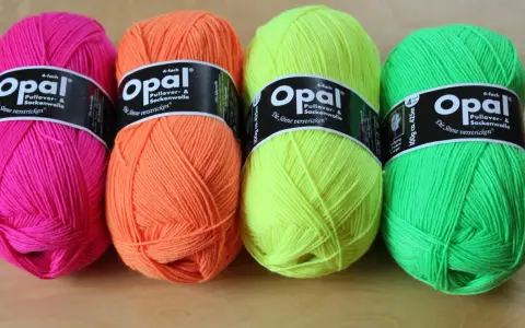 Four balls of Opal yarn in bright pink, orange, yellow, and green.