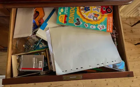 En låda fylld med pysselmaterial, papper, en bok med bondgårdstema och klistermärken, samt en burk med nålar och **påsklämmor**.