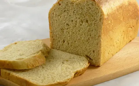 Frisch gebackenes Brot, das wie aus Buchweizen und anderen Getreidesorten gemacht aussieht, liegt auf einem Holzbrett.