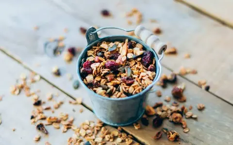 Un cubo metálico lleno de granola casera, con arándanos y semillas. ¡Perfecto para saber como hacer granola!