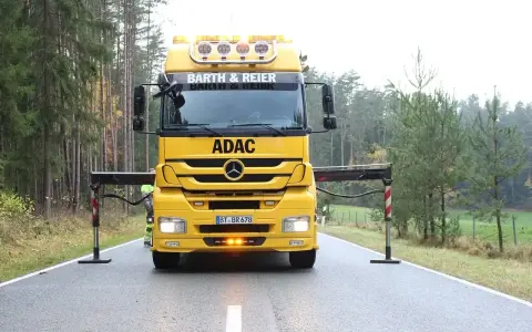 Żółta ciężarówka ADAC z wysięgnikiem przygotowana do holowania na drodze ekspresowej.
