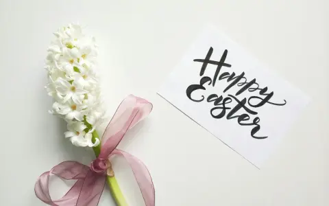 Un giacinto bianco legato con un nastro rosa, accanto a un biglietto con scritto "Happy Easter". Come una poesia campane di Pasqua di Gianni Rodari.