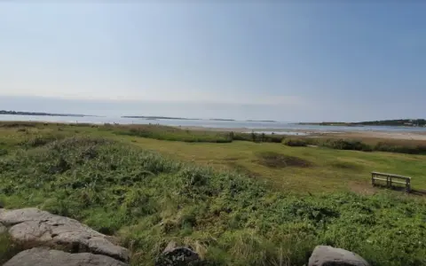 En bänk vid Rågelunds camping bjuder in till en stunds avkoppling med utsikt över vatten och grönska.