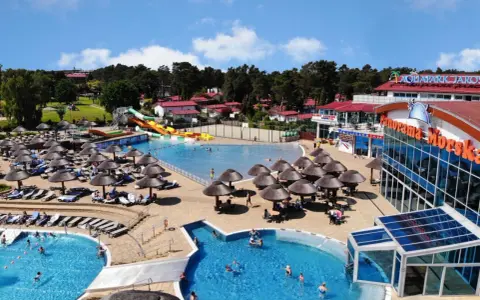 Aquapark w Jarosławcu: baseny, zjeżdżalnie i leżaki pod parasolami. Wiele osób korzysta z atrakcji, tworząc radosną atmosferę.