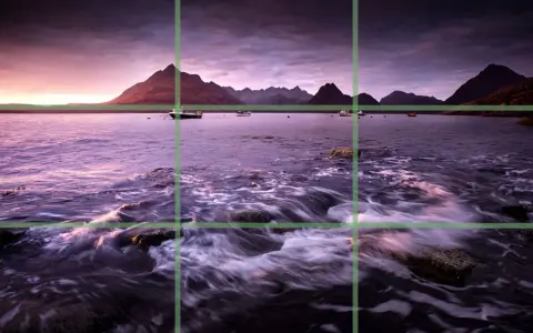 Paysage marin au crépuscule, avec des montagnes en arrière-plan et des bateaux sur l'eau. La composition suit la règle des tiers pour un équilibre visuel.