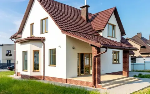 Biała elewacja z ceglanym cokołem i brązowym dachem. Klasyczne, ponadczasowe połączenie, które zawsze wygląda stylowo, pokazując najmodniejsze kolory elewacji.