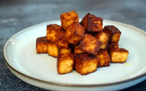 Goldbraun gebratene Tofuwürfel auf einem Teller, perfekt zum tofu zubereiten.
