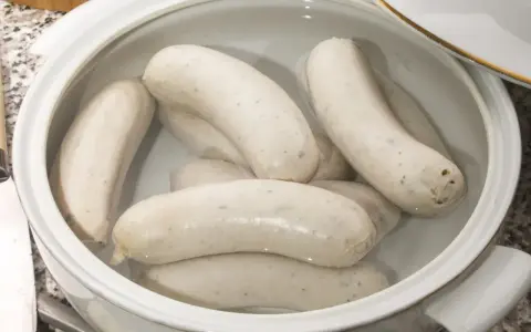 Biała kiełbasa w garnku z wodą, gotowa do parzenia. Idealny sposób, jak sparzyć białą kiełbasę, by była soczysta i smaczna.
