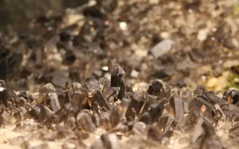 Cristalli di quarzo fumè, noti per le loro proprietà di radicamento e protezione, emergono da una base rocciosa.