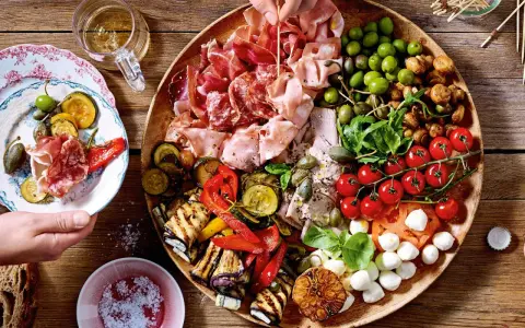 Große Platte mit Antipasti: Wurst, Schinken, Oliven, gegrilltes Gemüse, Tomaten, Mozzarella. Perfekt für Antipasti Rezepte.