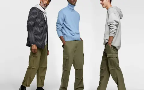 Tres hombres posan con pantalones cargo y camisas. Uno lleva un blazer a rayas, otro un suéter azul y el tercero una sudadera gris.