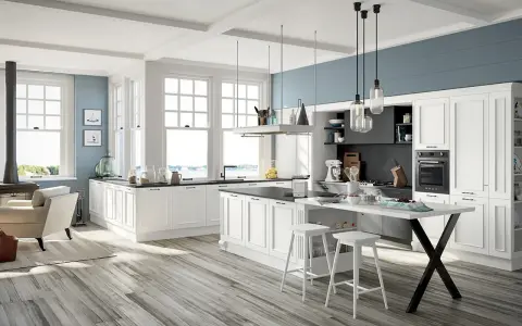 Cucina luminosa con isola centrale, sgabelli bianchi e una nicchia sotto finestra con vista mare.