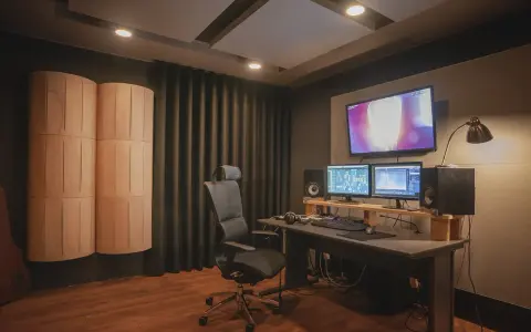 Studio do tworzenia dźwięku z monitorami, komputerem i panelem akustycznym. Idealne miejsce do pracy nad sound designem.