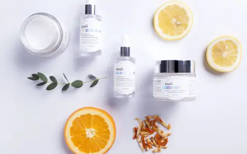Hudvårdsprodukter från Klairs med C-vitaminserum och en kräm med e-vitamin hud för lyster. Citron- och apelsinskivor som dekoration.