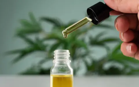 Une goutte d'huile essentielle tombe d'un compte-gouttes dans un flacon. Un remède naturel pour la toux grasse.