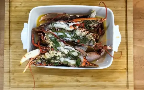Homards bleus préparés dans un plat blanc, prêts pour une recette savoureuse.