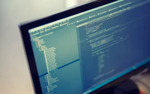 Programista pracuje nad kodem PHP. Format komputera pozwala na szybkie tworzenie i edycję skomplikowanych projektów.