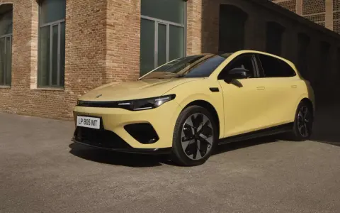 Żółty Leapmotor B05 z czarnym dachem i felgami, zaparkowany przed ceglanym budynkiem.