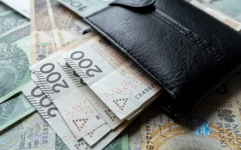 Czarny portfel na stosie polskich banknotów 200 zł. Wiele wskazuje na podwyżkę najniższej krajowej.