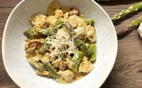 Pyszne makaron farfalle ze szparagami i kurczakiem w kremowym sosie, posypany startym parmezanem.
