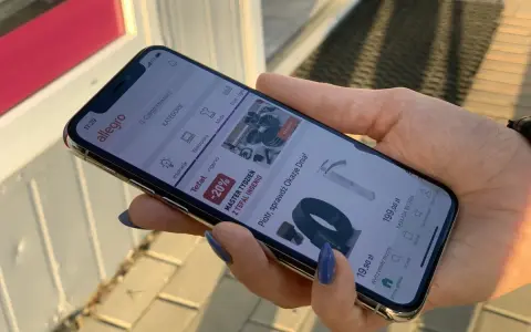 Dłoń trzyma iPhone 11, na ekranie aplikacja Allegro. Idealne iphone 11 wymiary do przeglądania ofert.