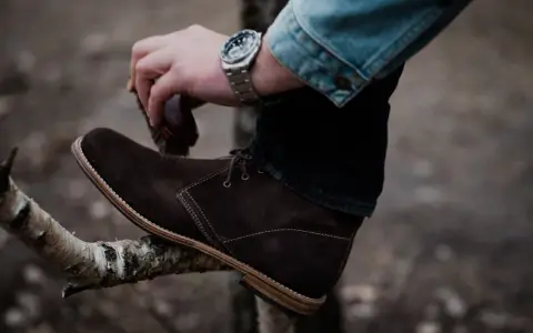 Hombre cepillando bota de cuero marrón, un paso esencial para saber como limpiar botas de cuero y mantenerlas impecables.