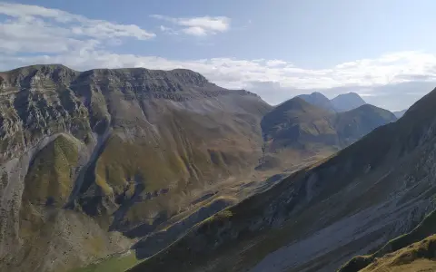 Vaste montagne del Monte Corvo sotto un cielo azzurro con nuvole bianche.