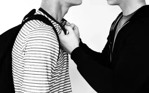 Due persone, una con una felpa nera, afferra l'altra per il colletto. Un'immagine che evoca la psicologia delle persone aggressive.