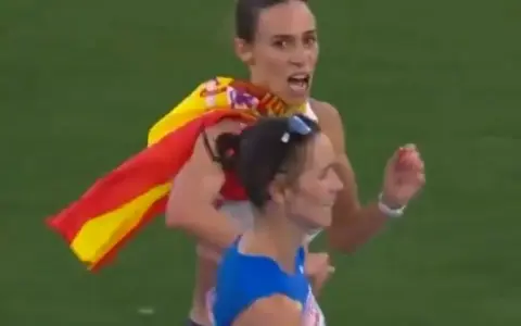 Laura García Caro celebra su victoria en atletismo, ondeando la bandera española con orgullo.