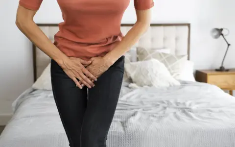 Mujer con las manos en el abdomen, sintiendo dolor de ovarios y gases.