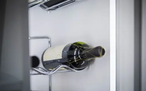 Eine Flasche Rotwein liegt auf einem Chromgestell. Der Wein ist bereits geöffnet, was man an der leichten Oxidation erkennen kann.