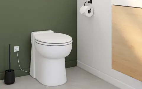Toilettes modernes avec un sanibroyeur discret, dont le fonctionnement est assuré par une prise électrique visible.