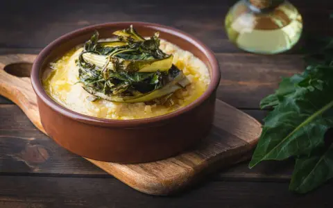 Polenta cremosa con cicoria in padella, un piatto rustico e saporito.