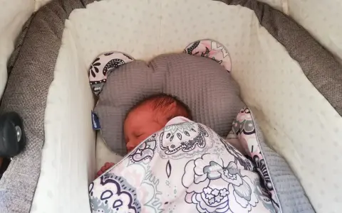 Malutkie dziecko śpi w wózku, otulone kolorowym kocykiem. To pierwszy spacer, czas na drzemkę.