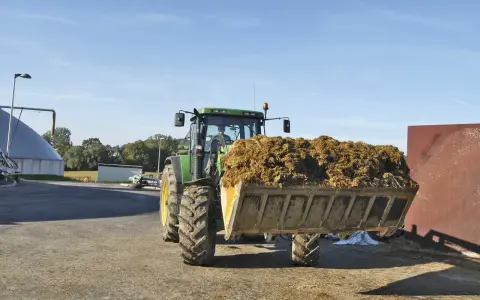 Traktor mit vollem Ladebehälter, bereit für die Biogasanlage. Mais und Gülle werden verarbeitet.