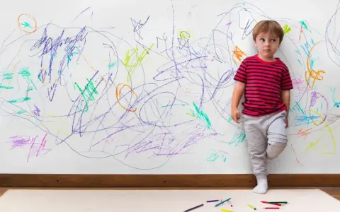 Chłopiec z ADHD, stojący przy ścianie pokrytej kolorowymi bazgrołami, wyraża swoje emocje.