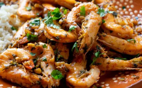 Langostinos en salsa, jugosos y llenos de sabor, servidos con arroz blanco. Un plato que invita a disfrutar.