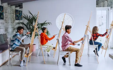 Des enfants concentrés sur leur peinture sur petite toile facile, chacun sur son chevalet, dans un atelier lumineux.