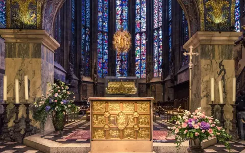 Wnętrze katedry z ołtarzem i witrażami. Wzrok przyciąga złota szkatuła, przypominająca o treści psalmu 137.